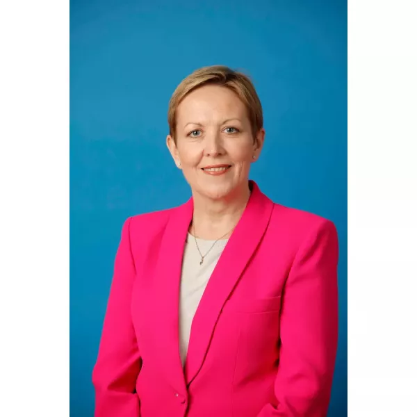 Photo of Sandra O'Malley wearing a pink blazer on blue background