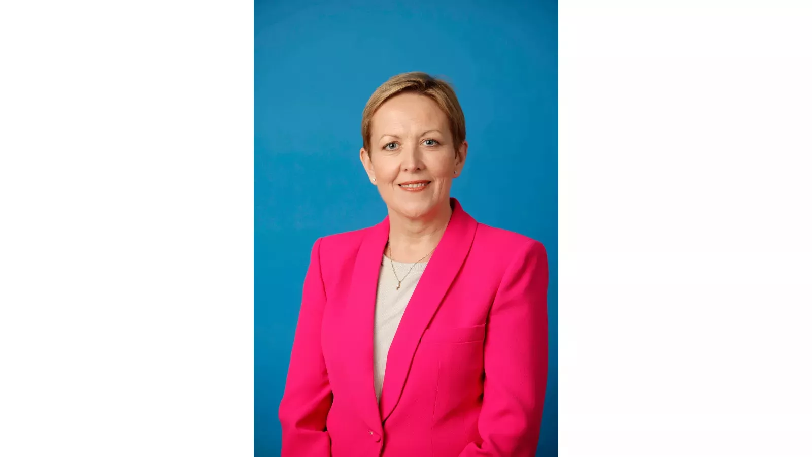 Photo of Sandra O'Malley wearing a pink blazer on blue background